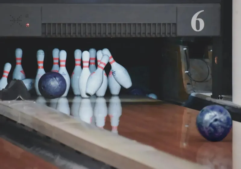 Skupina přátel hrající bowling v moderní herně